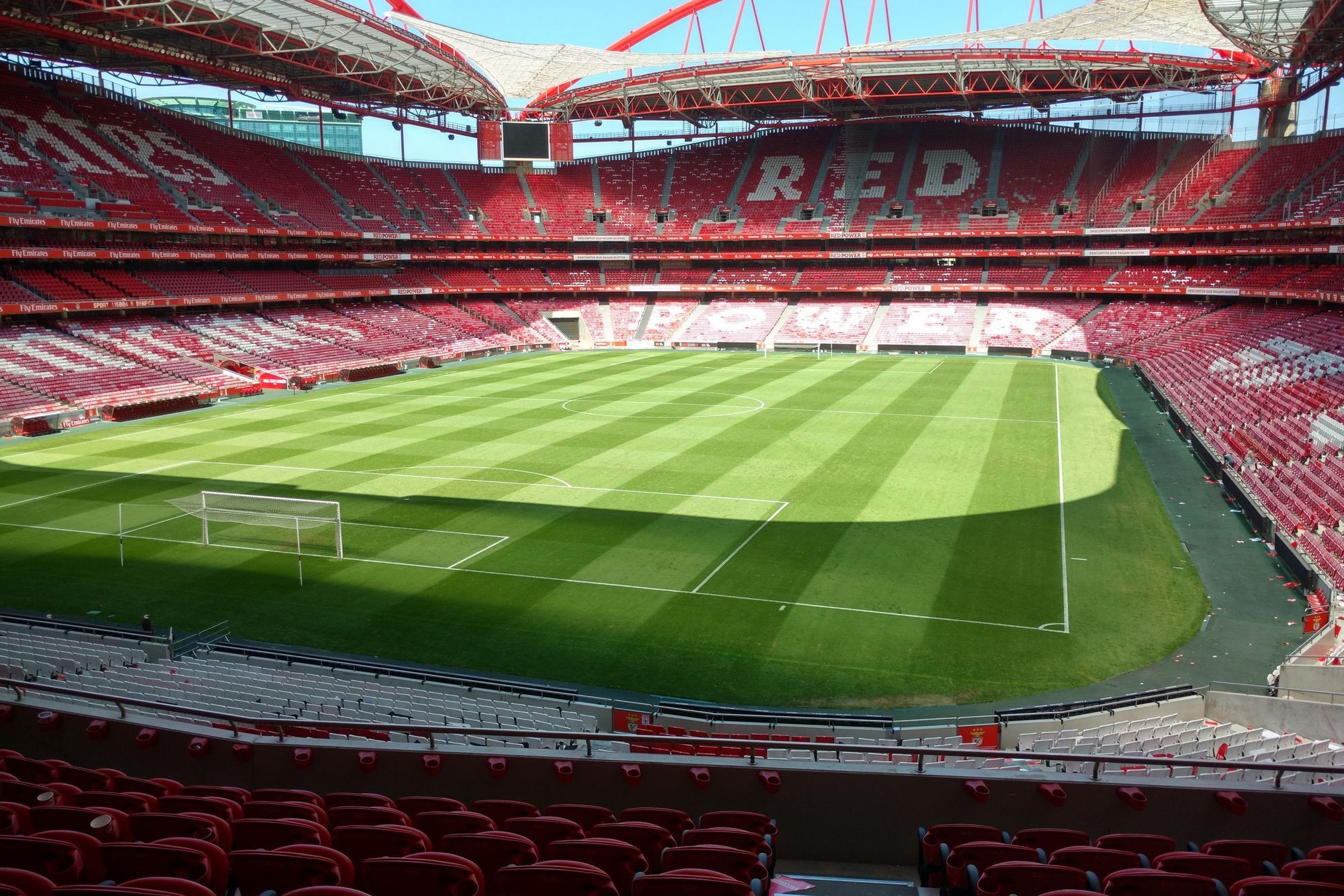The empty Estádio da Luz in Lisbon with its red stands and a freshly mown pitch
