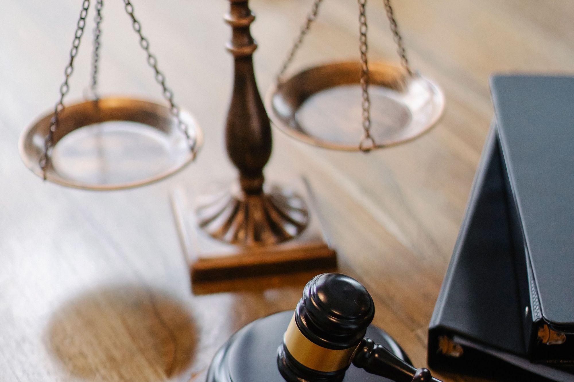 Brass scales of justice and a gavel on a wooden desk