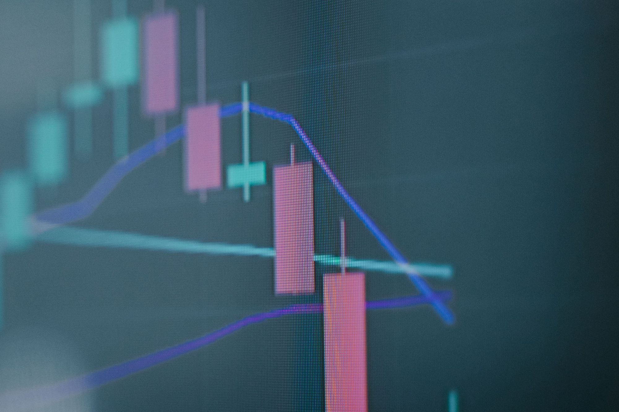 A falling candlestick price chart on a dark screen